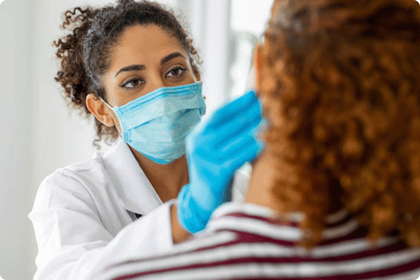 Doctor wearing surgical mask examining curly red-haired patient